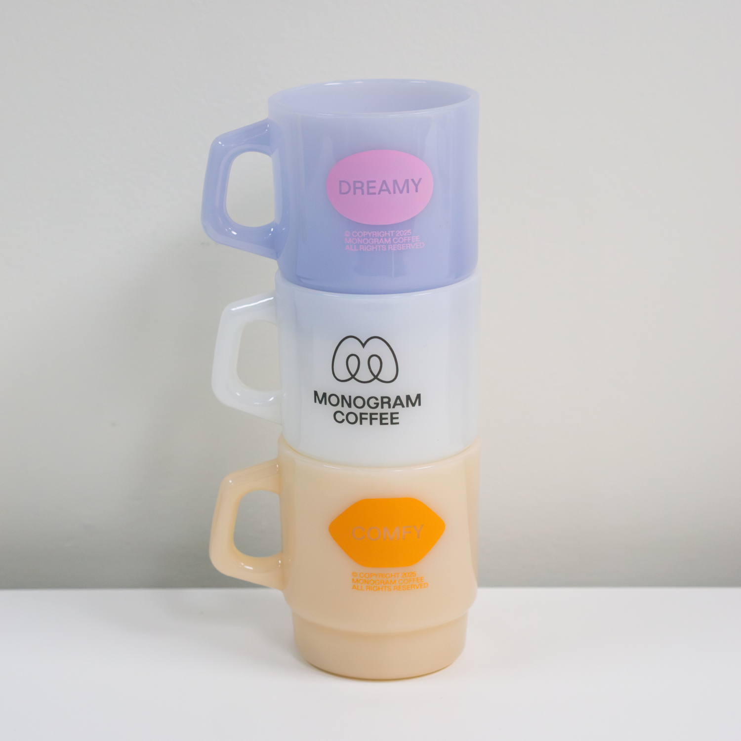 Stack of three colorful coffee cups with visible branding on a white background
