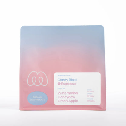 A blue and pink gradient bag of Monogram Candy Blast decaf espresso, an anaerobic co-ferment from Colombia (Caturra and Colombia varieties) with tasting notes of watermelon, honeydew, and green apple.