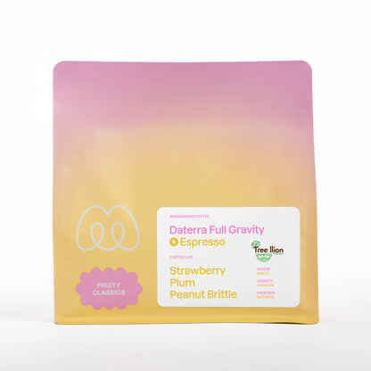A pink, orange, and yellow pastel gradient bag of Monogram Daterra Full Gravity espresso coffee, a natural processed coffee from Brazil with fruity classics flavor profile and tasting notes of strawberry, plum, and peanut brittle.